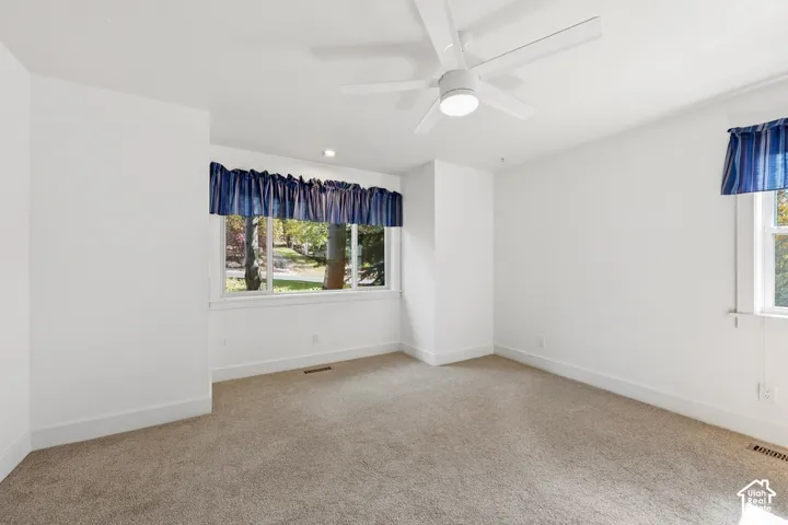 Room featuring neutral carpeting, white wall finishes, and a central ceiling fan with an integrated light fixture