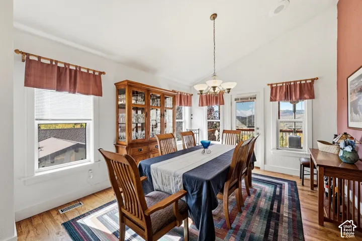 Vaulted ceilings, wood-finish flooring, multi-pane windows, and a multi-light hanging chandelier