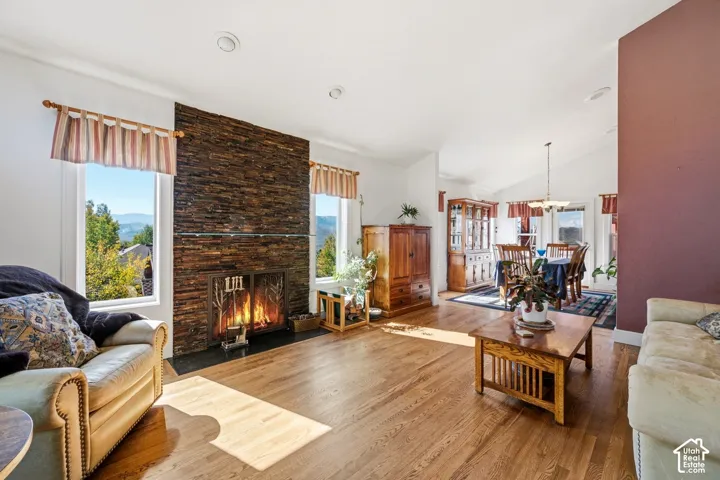 Floor-to-ceiling textured stone fireplace surround, wood-finish flooring, vaulted ceilings, and expansive windows