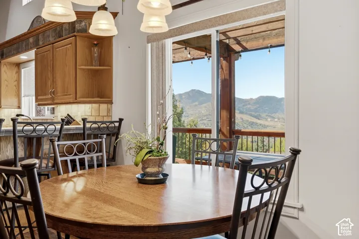 Kitchen featuring medium-tone wood cabinetry, tile backsplash, and built-in breakfast bar, paired with sliding glass doors opening to a deck with mountain scenery