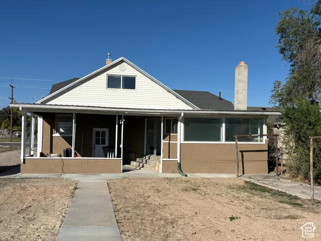 Gabled roofline with white siding, covered front porch, concrete walkway