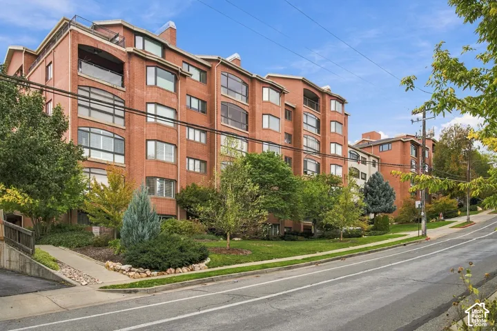 Multi-story brick exterior featuring large arched windows, recessed balconies, and manicured landscaping