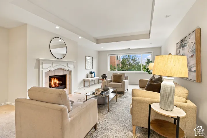 Living room featuring a tray ceiling, recessed lighting, and a fireplace with a decorative mantel and tile surround
