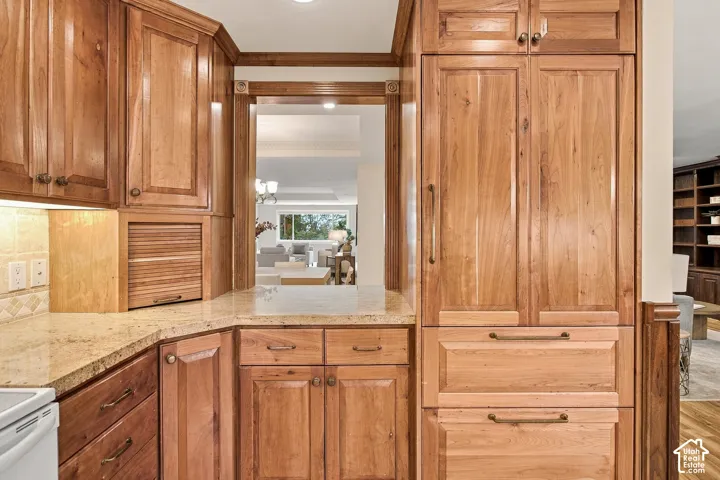 Natural wood cabinetry with a built-in appliance panel, stone countertops, and a tambour door appliance garage