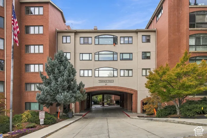Multi-story brick exterior featuring a recessed concrete driveway, arched masonry detailing, and arched-top windows