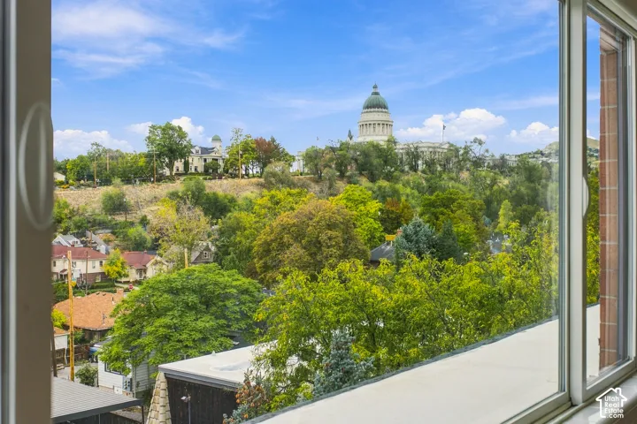 Expansive sightline featuring the state capitol building, mature trees, and urban surroundings, framed by a large multi-pane window