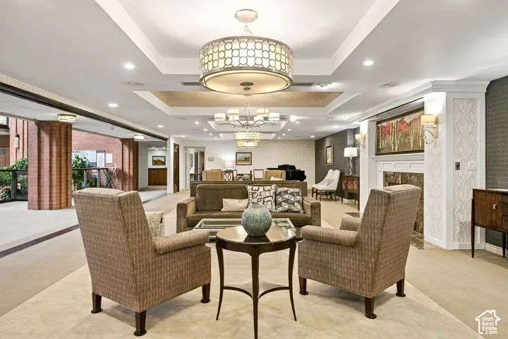 Tray ceiling with recessed lighting, tiered geometric drum chandeliers, and a fireplace with a stone surround