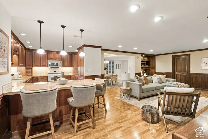 Kitchen featuring wood cabinetry, stone-surface breakfast bar, recessed lighting, pendant fixtures, and wood-finish flooring
