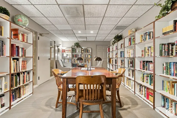 Floor-to-ceiling built-in shelving, suspended drop ceiling, and neutral carpeting