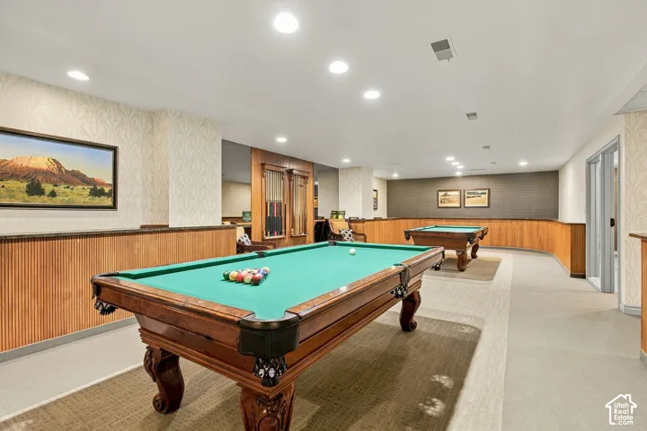 Large recreation space featuring recessed lighting, extensive wood-paneled wainscoting, textured wallpaper, and inset wall cabinetry