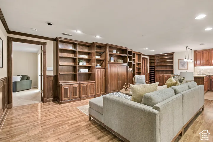 Custom floor-to-ceiling wooden built-in cabinetry featuring shelving, enclosed storage, and an integrated wine rack, complemented by wood-finish flooring and traditional wood trim detailing