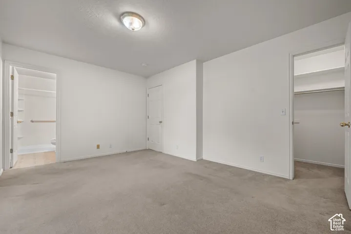 Neutral-toned carpet flooring, crisp white walls, flush-mount ceiling lighting, and two interior closets featuring built-in shelving
