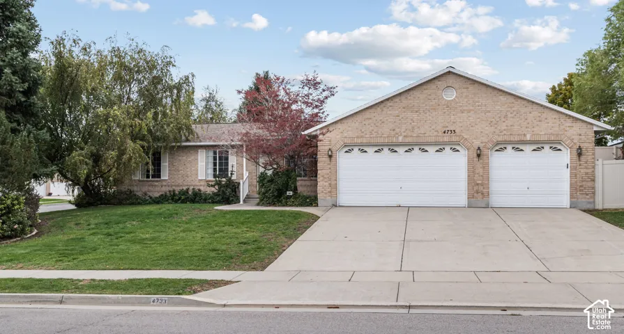 Single-story brick exterior featuring a front-facing attached two-car garage, concrete driveway, and established landscaping