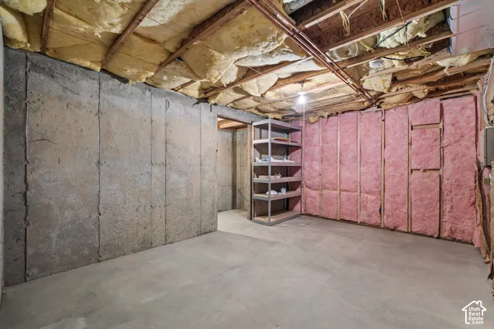Unfinished lower level featuring concrete foundation walls, exposed joists, and fiberglass batt insulation