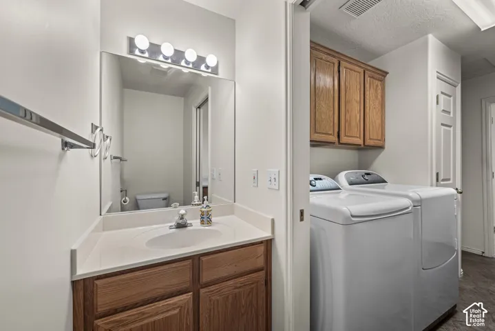 Bathroom featuring a vanity with wood-finish cabinetry, a solid-surface countertop with an integrated oval sink, and a large wall-mounted mirror