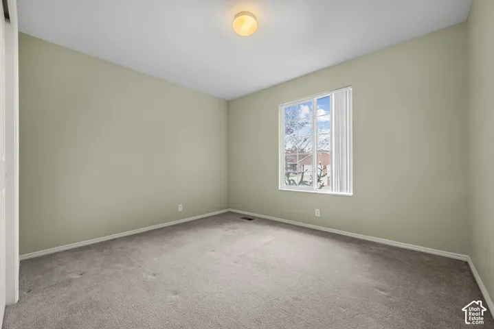 Room featuring wall-to-wall carpeting, neutral paint finish, single-pane window with vertical blinds, and a flush-mount ceiling light fixture