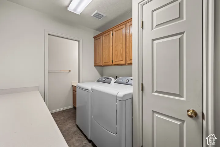 Laundry room featuring wood-finish cabinetry, solid-surface countertop with integrated backsplash, and neutral flooring