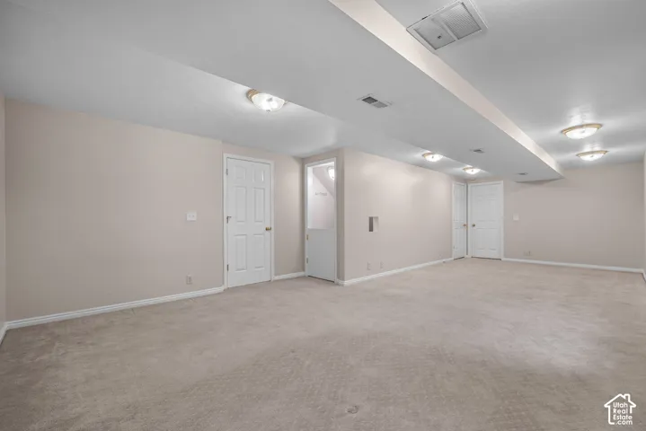 Neutral-toned room with wall-to-wall carpeting, flush-mount ceiling lighting, and multiple interior paneled doors