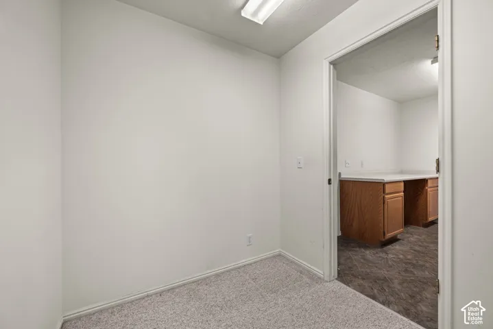 Interior space featuring neutral wall tones, textured carpet flooring, and a flush-mount overhead light fixture