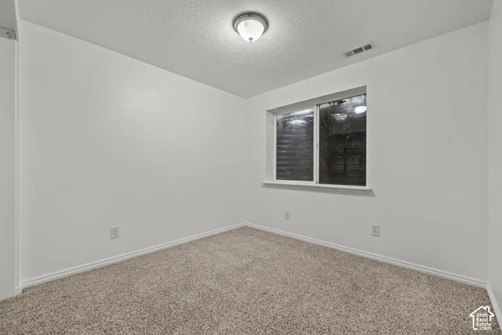 Neutral-toned carpeted flooring, white wall finish, and a sliding window with a window well