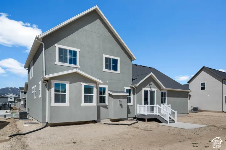 Multi-story exterior featuring gray stucco siding, a gabled roofline, multi-pane windows with white trim, and a raised wooden deck with white railings