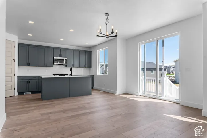 Kitchen featuring charcoal-toned cabinetry, a center island, white subway tile backsplash, recessed lighting, and wood-finish flooring