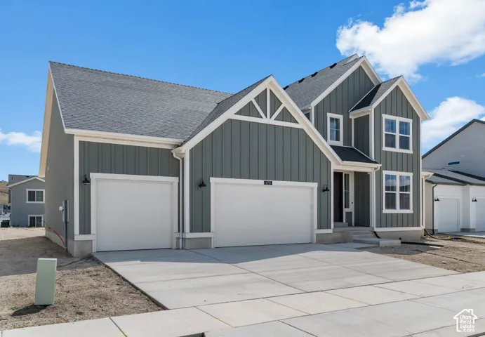 Two-story exterior featuring vertical board-and-batten siding, contrasting trim, a multi-gabled roofline, and an attached three-car garage