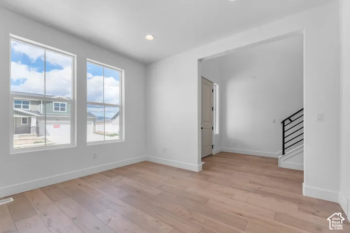 Interior space featuring wood-finish flooring, dual windows, recessed lighting, and a staircase with a black metal railing