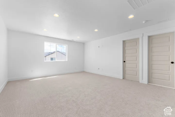 Neutral interior space featuring high-pile carpeting, recessed lighting, white walls, and two five-panel interior doors
