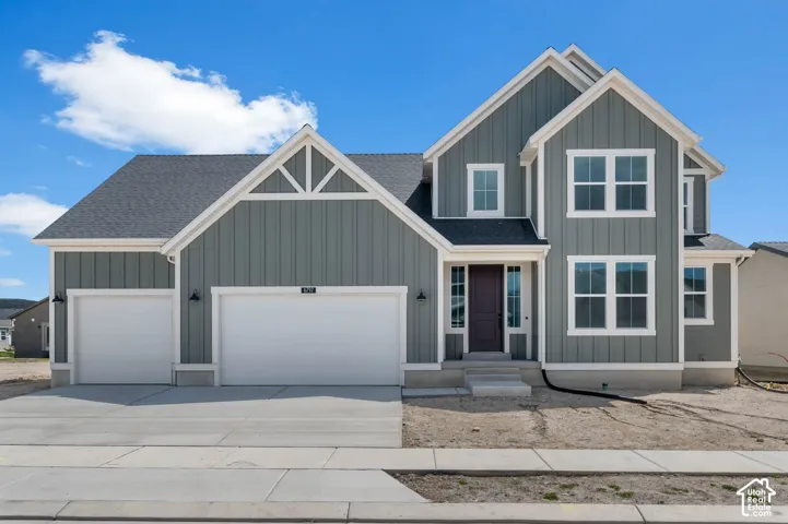 Two-story exterior featuring vertical board-and-batten siding, contrasting white trim, multiple gables, and a three-car garage