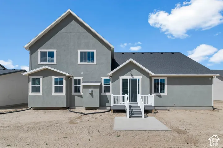 Multi-level exterior featuring grey stucco siding, white trim detailing, a dark shingled roof, sliding glass doors, and an elevated composite deck with white railings