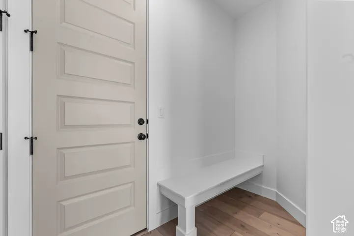 Paneled interior door with matte black hardware, built-in bench seating, and wood-finish flooring