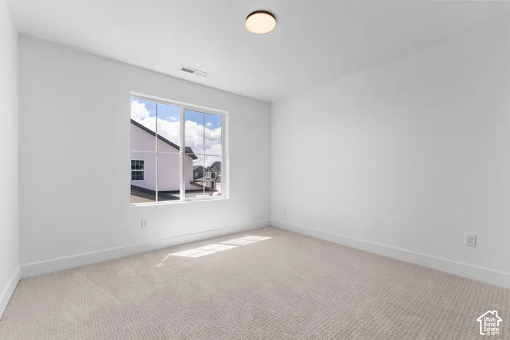 Neutral-toned carpeting, crisp white wall finishes, and a single-pane window with a muntin grid detail, illuminated by a flush-mount circular ceiling fixture