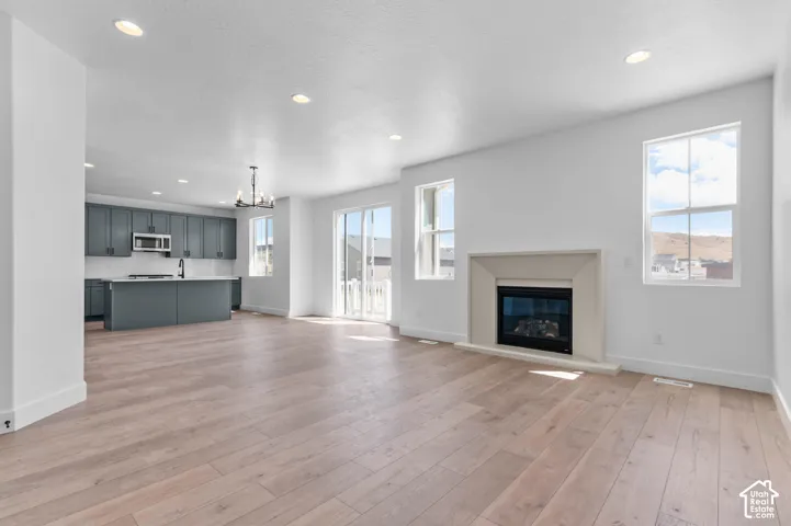 Wood-finish flooring, recessed lighting, fireplace with a tiered surround, grey cabinetry, and a kitchen island