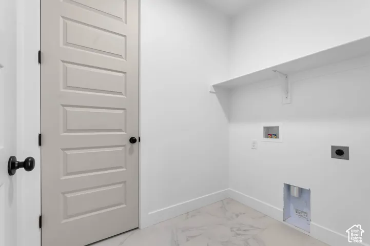 Utility room featuring large-format tile flooring, built-in shelving, and a neutral-toned paneled door with matte black hardware