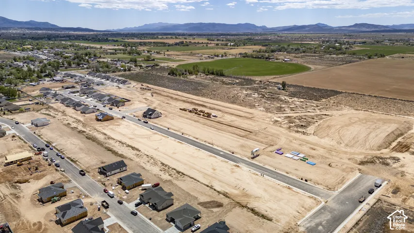 Aerial perspective of a development site featuring paved roads, expansive plots, and a mountainous backdrop