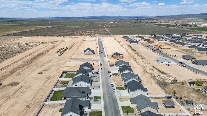 Aerial perspective of a developing residential community featuring paved streets, asphalt-shingled roofing, concrete driveways, and established landscaping