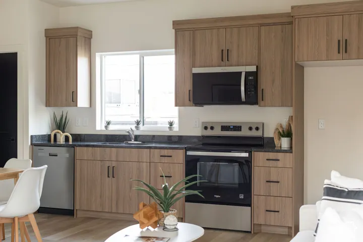 Kitchen featuring wood-finish cabinetry, dark stone-style countertops, stainless steel appliances, and a window above the sink