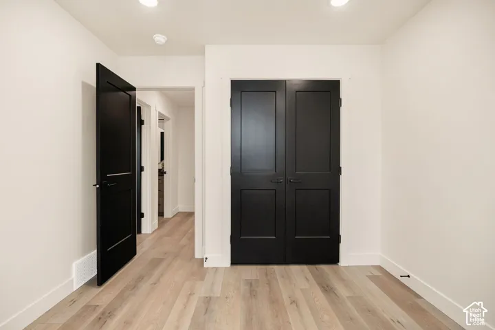 Neutral interior featuring wood-finish flooring, two-panel black interior doors, and recessed ceiling lighting