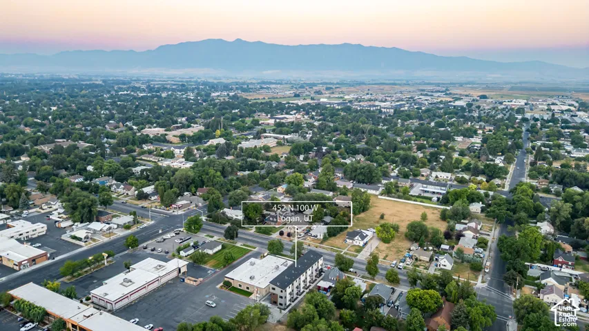 Aerial perspective featuring a multi-story structure with a pitched roof and mountain backdrop