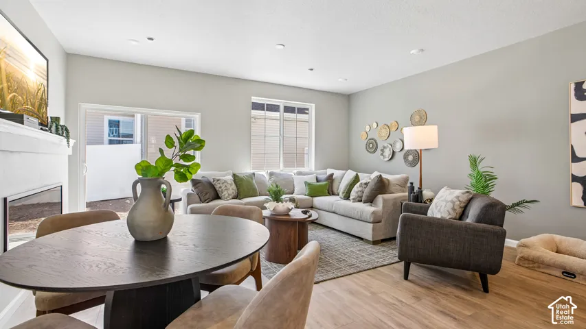 Living area featuring wood-finish flooring, recessed lighting, a fireplace with a white mantel, and a sliding glass door