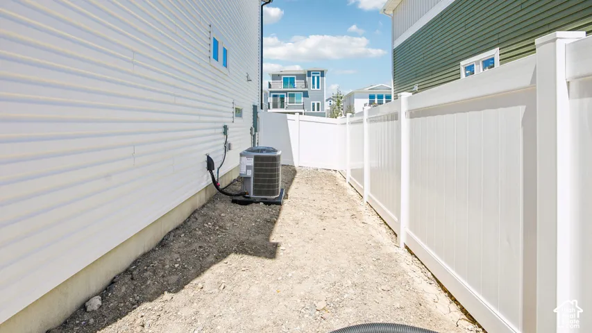 Side yard featuring white vinyl privacy fencing and an exterior heating and cooling unit