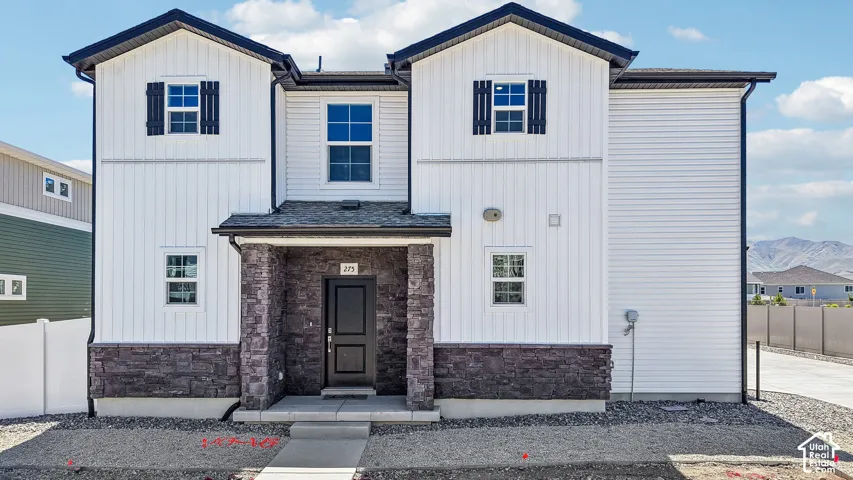 Two-story exterior featuring board-and-batten siding, stone veneer accents, dark-toned shutters, a covered entryway, and asphalt shingle roofing