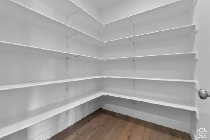 Walk-in storage featuring multi-level wrap-around shelving, white finish walls, and wood-finish flooring