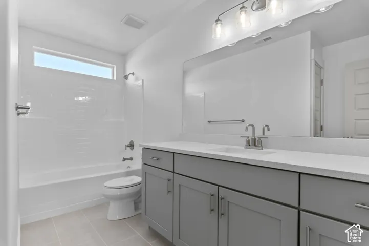 Gray shaker-style vanity with a solid surface countertop, integrated sink, full-width mirror, and subway-tiled shower surround with a clerestory window