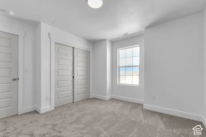 Neutral interior featuring wall-to-wall carpeting, multi-panel doors, thick window casing, and a single-hung grid window