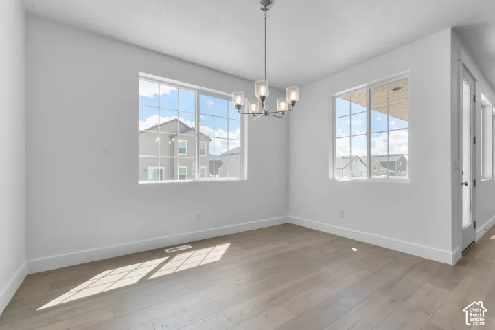 Neutral-toned wood-finish flooring, sliding glass exterior door, multi-pane windows, and a five-arm metal chandelier