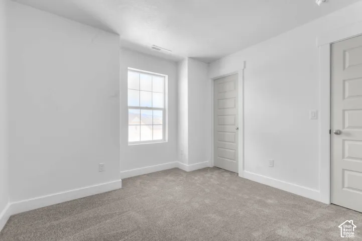Neutral-toned carpeted flooring, multi-pane window, and white interior doors with five-panel detailing