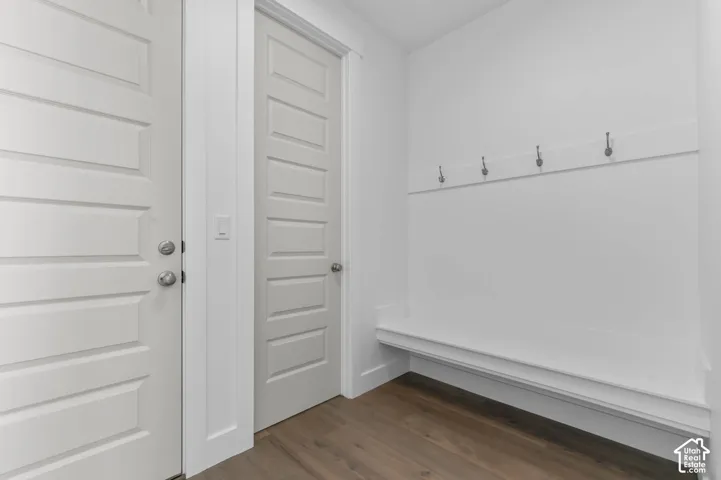 Built-in storage bench with wall-mounted coat hooks, wood-finish flooring, and five-panel interior doors with satin nickel hardware