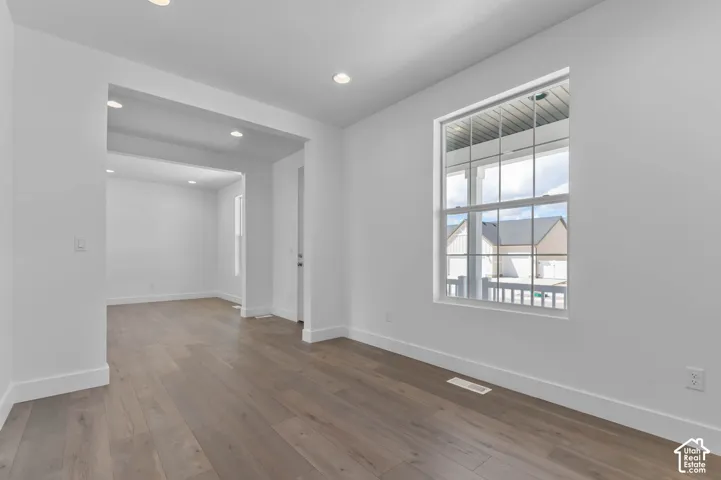 Open floor plan featuring wood-finish flooring, recessed lighting, and a window with colonial-style muntins